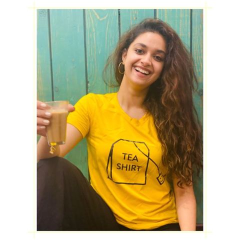 Keerthy Suresh in a yellow t-shirt poses a picture with a cup of tea.